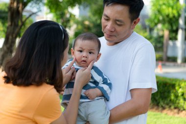 Küçük çocuklu ebeveynler parkta dinleniyor ve eğleniyorlar.