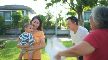 Küçük çocuklu büyükanne ve büyükbaba bir parkta eğleniyor ve dinleniyorlar.