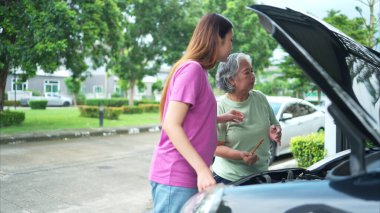 Büyükanne ve torun, anne ve babalarının otomobillerini kontrol etmek için birbirlerine yardım ediyorlar.