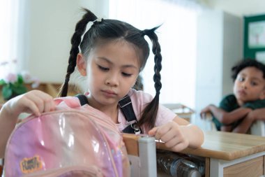 Sırt çantasıyla sınıf için hayati eşyaları depolayan bir okul çocuğu..