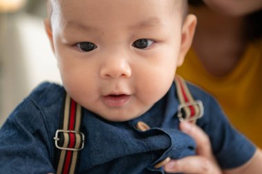 Küçük bir çocuk neşeyle oyuncaklarla oynuyor salonun zemininde annesiyle.