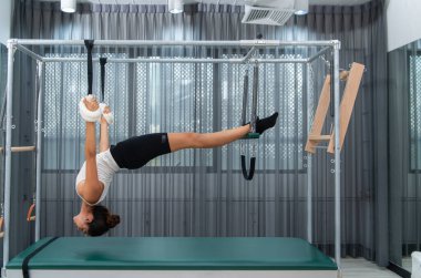 Pilates Cadillac 'ı üzerinde pilates yapan genç bir kadın.