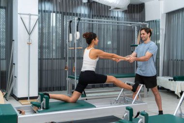 Genç bir adam ve genç bir kadın pilates egzersizleri yapıyorlar.