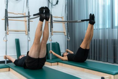 Genç bir adam ve genç bir kadın pilates egzersizleri yapıyorlar.