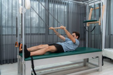 Genç bir adam pilates Cadillac 'ında pilates egzersizi yapıyor.