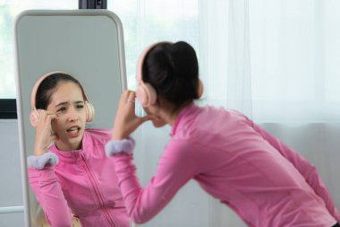 Pembe eşofmanlı bir kız bale öğrencisi en sevdiğiniz müzikle kulaklıkla dans ederek vücudu ısıtıyor.