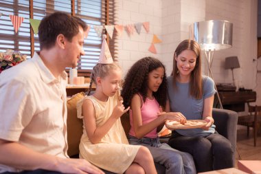 Ebeveynler ve çocuklar doğum günü partisinin tadını çıkarıyorlar.