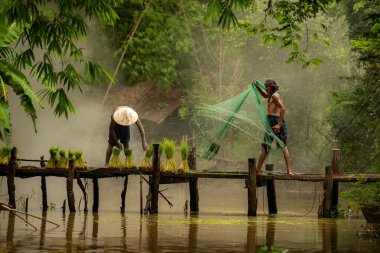Çiftçi, nehirde balık yakalamak için balık ağı kullanan balıkçıya yardım eder ve onunla konuşur.