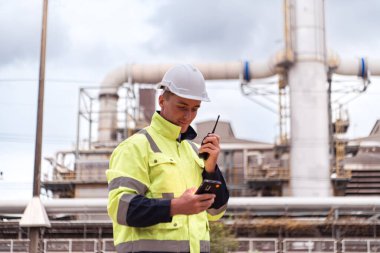 Petrol mühendisi büyük bir petrol rafinerisinde petrol arıtma tesisini teftiş ediyor.