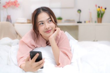 Asyalı genç bir kadın yatak odasında yatmadan önce dinleniyor.