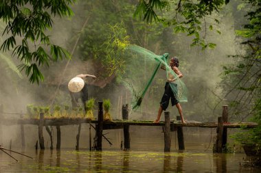 Çiftçi, nehirde balık yakalamak için balık ağı kullanan balıkçıya yardım eder ve onunla konuşur.