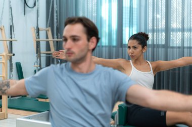 Genç bir adam ve genç bir kadın pilates egzersizleri yapıyorlar.