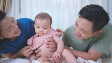 Havlunun üzerinde mutlu bir şekilde bekleyen küçük bir çocuk banyo yaptıktan sonra pudra sürer ve elbiselerini giyer.