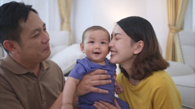 Ebeveynler ve küçük çocukları evin oturma odasında mutlu bir şekilde oynuyorlar.