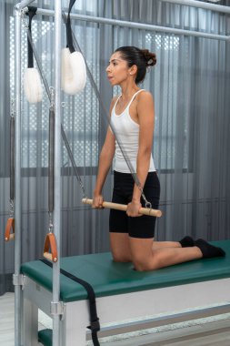 Pilates Cadillac 'ı üzerinde pilates yapan genç bir kadın.