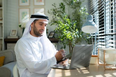 Evde dizüstü bilgisayarda çalışan genç Arap işadamının portresi