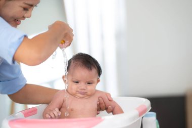 Bir anne küçük bir çocuk küvetinde kızını yıkıyor..