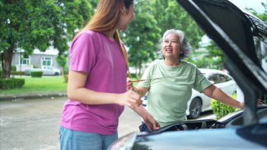 Büyükanne ve torun, anne ve babalarının otomobillerini kontrol etmek için birbirlerine yardım ediyorlar.