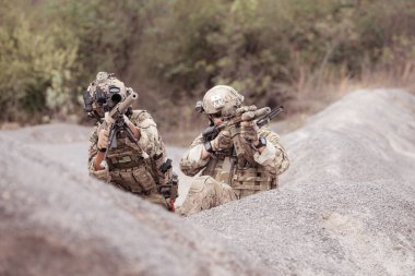 Kamuflaj üniformalı askerler silah taşıyorlar engebeli dağlarda keşif görevleri, saldırı piyade eğitimi alıyorlar..
