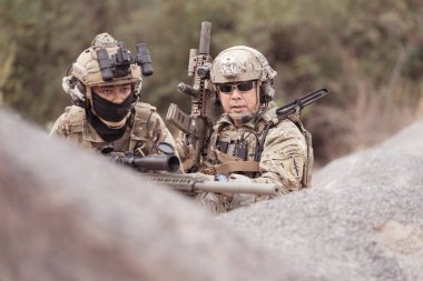 Kamuflaj üniformalı askerler silah taşıyorlar engebeli dağlarda keşif görevleri, saldırı piyade eğitimi alıyorlar..