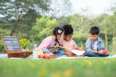 Mutlu bir aile parkta piknik yapıyor, Çocuklar kağıda resim çizerken eğleniyor..