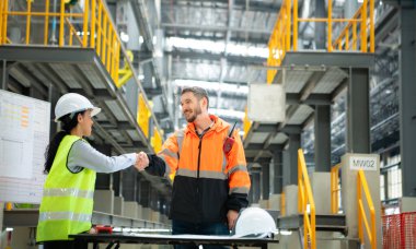 Erkek ve kadın mühendisler bir elektrik tamir istasyonunda birlikte çalışıyorlar, elektrik tren tamir programının detaylarını kontrol edin..