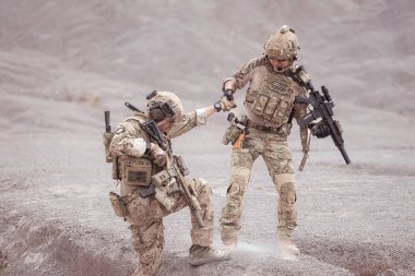 Kamuflaj üniformalı askerler silah taşıyorlar engebeli dağlarda keşif görevleri, saldırı piyade eğitimi alıyorlar..