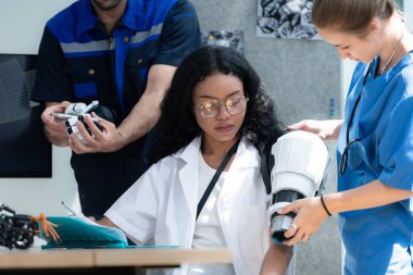 Engineers, doctors and physical therapists brainstorm ideas to design a robot with arm and hand organs, To be utilized for additional testing on patients. clipart