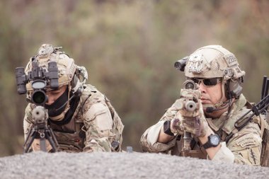 Kamuflaj üniformalı askerler silah taşıyorlar engebeli dağlarda keşif görevleri, saldırı piyade eğitimi alıyorlar..