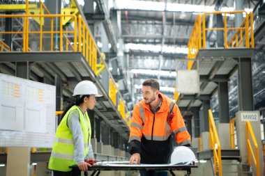 Erkek ve kadın mühendisler bir elektrik tamir istasyonunda birlikte çalışıyorlar, elektrik tren tamir programının detaylarını kontrol edin..