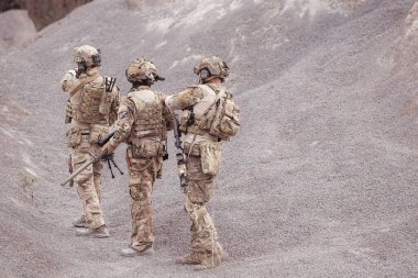 Kamuflaj üniformalı askerler silah taşıyorlar engebeli dağlarda keşif görevleri, saldırı piyade eğitimi alıyorlar..