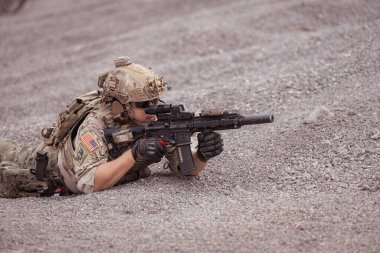 Kamuflaj üniformalı askerler silah taşıyorlar engebeli dağlarda keşif görevleri, saldırı piyade eğitimi alıyorlar..