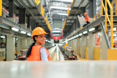 Gökyüzü tren tamir istasyonunda duran genç bir kadın mühendisin portresi..