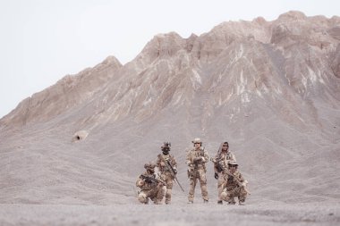 Kamuflaj üniformalı askerler silah taşıyorlar engebeli dağlarda keşif görevleri, saldırı piyade eğitimi alıyorlar..
