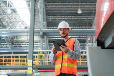 Tablet kullanan genç bir erkek teknisyenin portresi gökyüzü tamir istasyonunda çalışıyor ve ayakta duruyor..