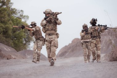 Kamuflaj üniformalı askerler silah taşıyorlar engebeli dağlarda keşif görevleri, saldırı piyade eğitimi alıyorlar..