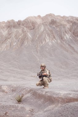 Kamuflaj üniformalı askerler silah taşıyorlar engebeli dağlarda keşif görevleri, saldırı piyade eğitimi alıyorlar..
