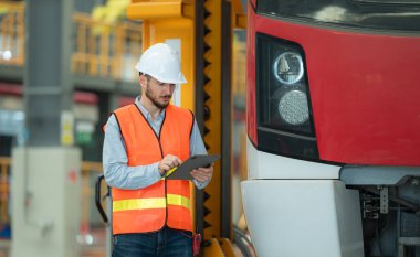 Tablet kullanan genç bir erkek teknisyenin portresi gökyüzü tamir istasyonunda çalışıyor ve ayakta duruyor..