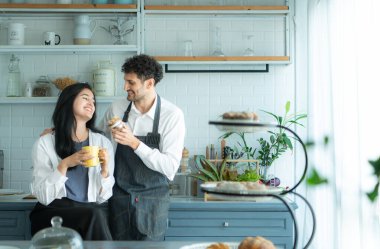Bir koca karısıyla yemek pişirirken önlük giyer. İkili kahve yudumlamak ve tamamlanmış ekmeği tatmak için mola verdi..