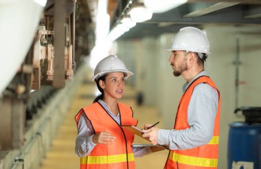 Erkek ve kadın mühendisler bir elektrik tamir istasyonunda birlikte çalışırlar. Garajda tamir edilen elektrikli trenin bagajını inceliyorum..