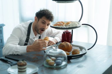 Genç bir adam karısıyla yemek yemek için tatlı yapmak için önlük giyer. Tamamlanmış tatlıyı kontrol ediyorum..
