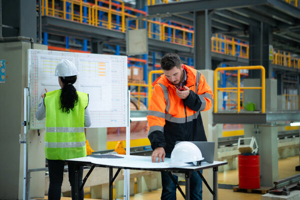 Male and female engineers work together in an electric repair station, Check the details of the electric train repair schedule.