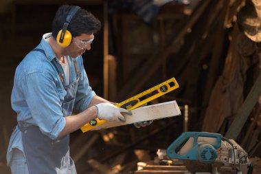 Atölyesinde ruh seviyesini tutan bir marangozun portresi.