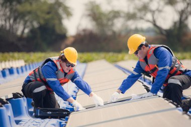 Fotovoltaik mühendisleri yüzen fotovoltaikler üzerinde çalışıyorlar. Suda yüzen güneş paneli ekipmanlarını incele ve onar.
