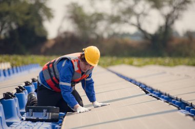 Fotovoltaik mühendisleri yüzen fotovoltaikler üzerinde çalışıyorlar. Suda yüzen güneş paneli ekipmanlarını incele ve onar.