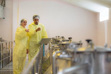 Şarap imalathanesinde çalışan olgun kadın ve erkek araştırmacılar ve geliştiriciler bir süredir mayalanan şarabı test ediyorlar..