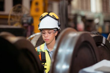 Üniformalı ve miğferli demiryolu teknisyeni tren atölyesindeki lokomotiflerden çıkarılan tren tekerleklerini inceleyin..