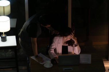 Gece vakti karanlık ofiste dizüstü bilgisayarla çalışan iş adamları..