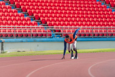 Disabled athletes prepare in starting position ready to run on stadium track clipart