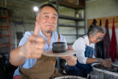 Baş parmağıyla çömlek üzerinde çalışan usta bir zanaatkarın portresi.